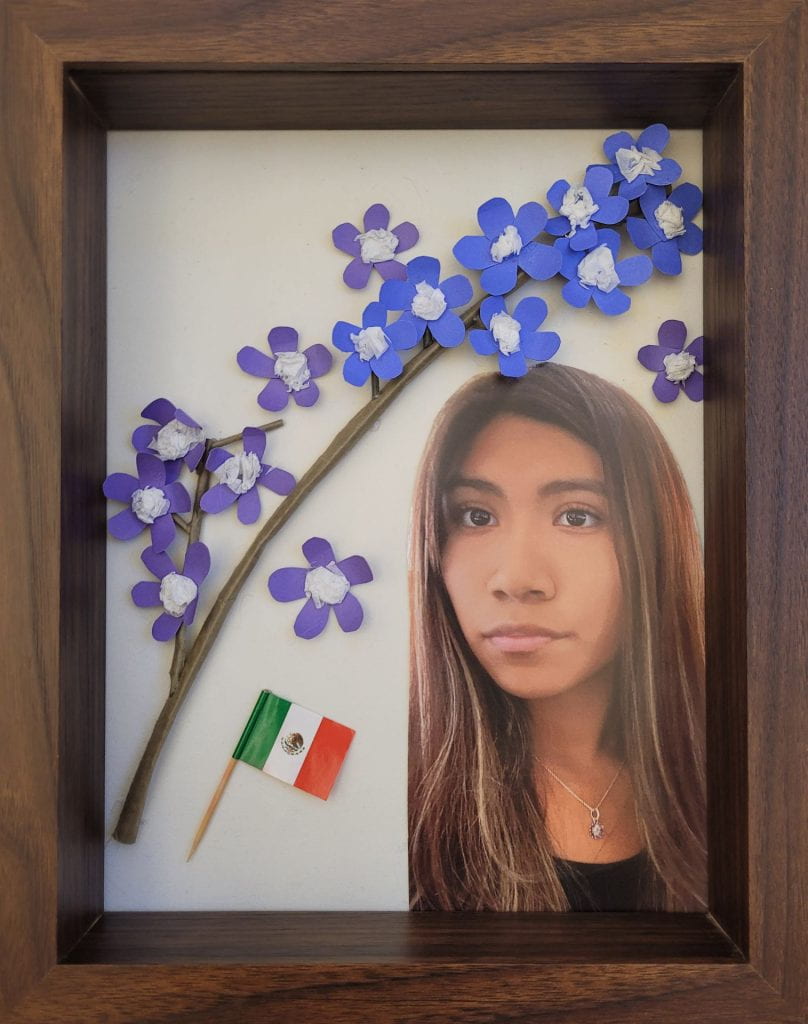 Paper flowers with a flag and photograph of artist, Shaylee Perez
