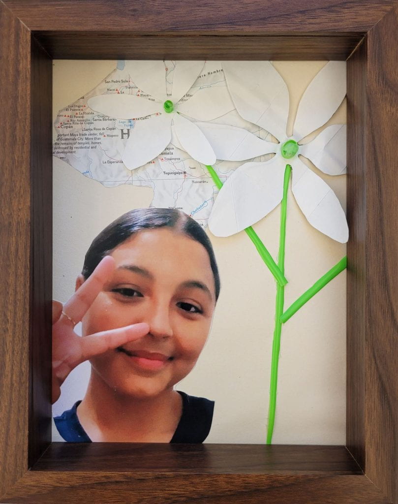 White paper flowers over a map and next to a photograph of artist Yaira Meija.