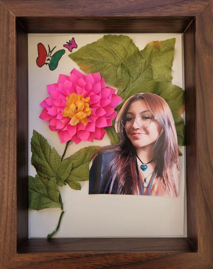 Paper flower next to photograph of artist, Andrea Rodriguez.
