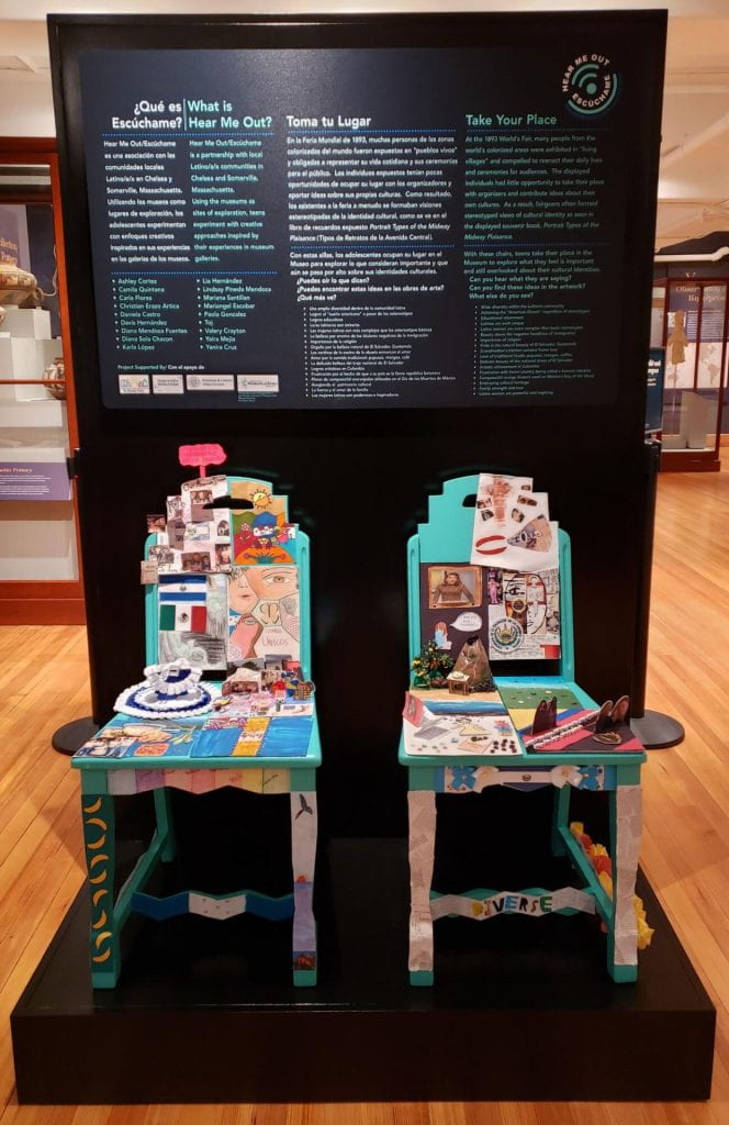 Two chairs decorated by Latino teens with bilingual text describing the project in the background.