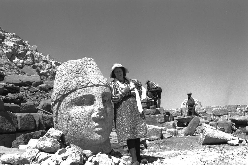 Black and white of Theresa B. Goell standing next to a large statue during an archaeological dig.