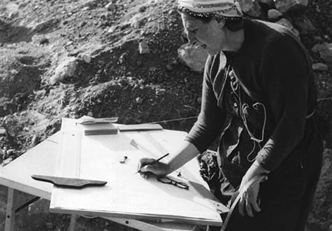 Theresa Goell, in the field, drawing the site at a table.