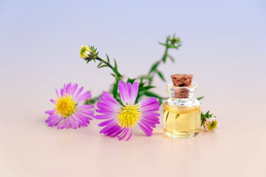Flowers with a vial of cosmetic oil.