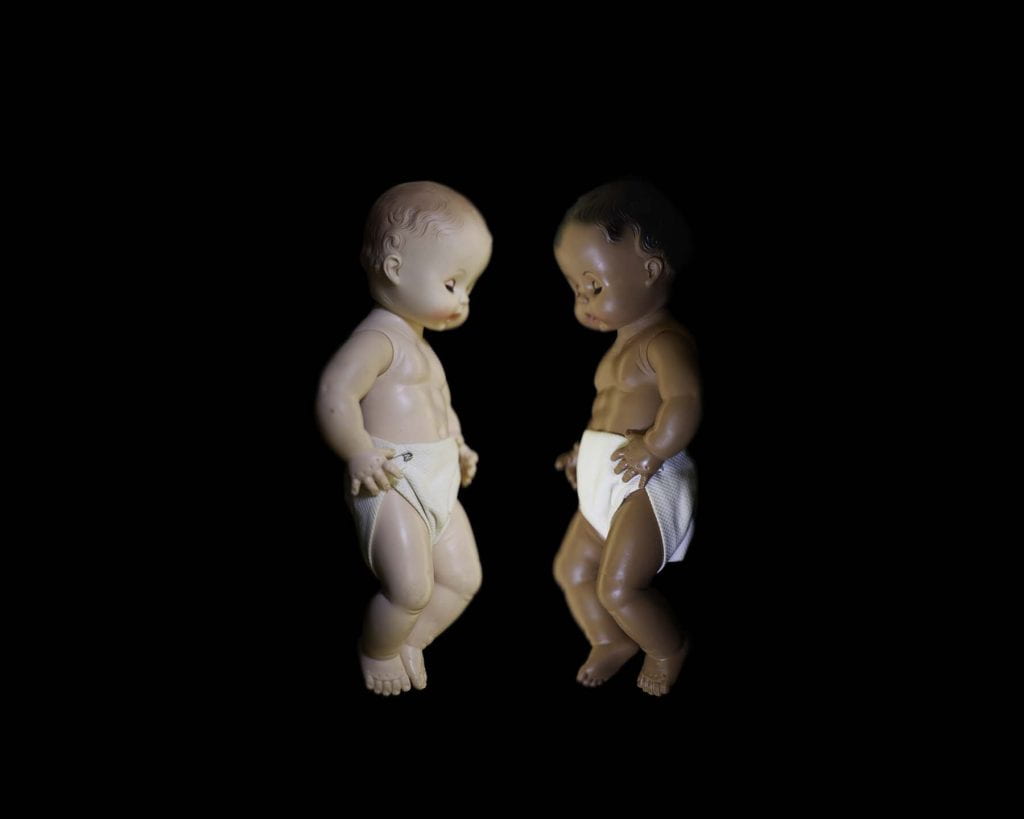 white and black baby dolls face each other.